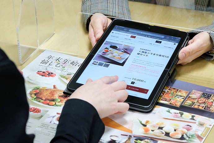 カタログとタブレットで一緒に返礼品探し。ご案内スタッフにはバイヤーもいるので、返礼品お悩みの方にはバイヤーがお好みを伺いながら直接ご提案する場面も。